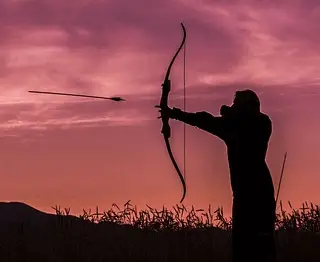 an archer shooting an arrow from a bow at twilight