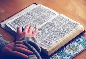 a person's hand resting on n open Bible