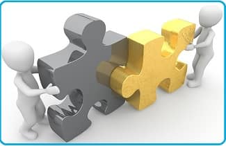 cooperation: two 3-dimensional figures of people fitting two puzzle pieces together