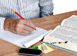 man taking notes and using a dictionary