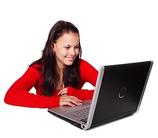 girl with a red sweater smiling as she reads her computer screen