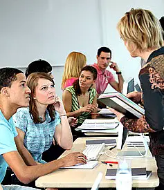 ESL teacher talking to her students at a long table.